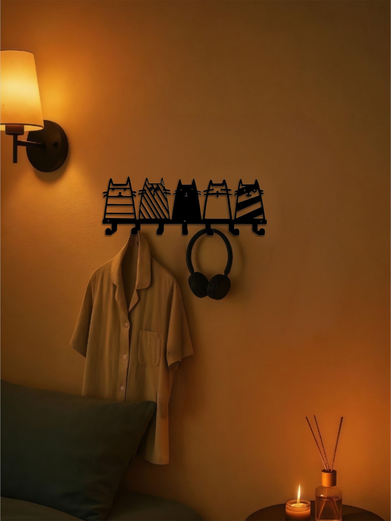 7-hook wall-mounted coat rack with cute cats design on a wall next to a lamp and plant.