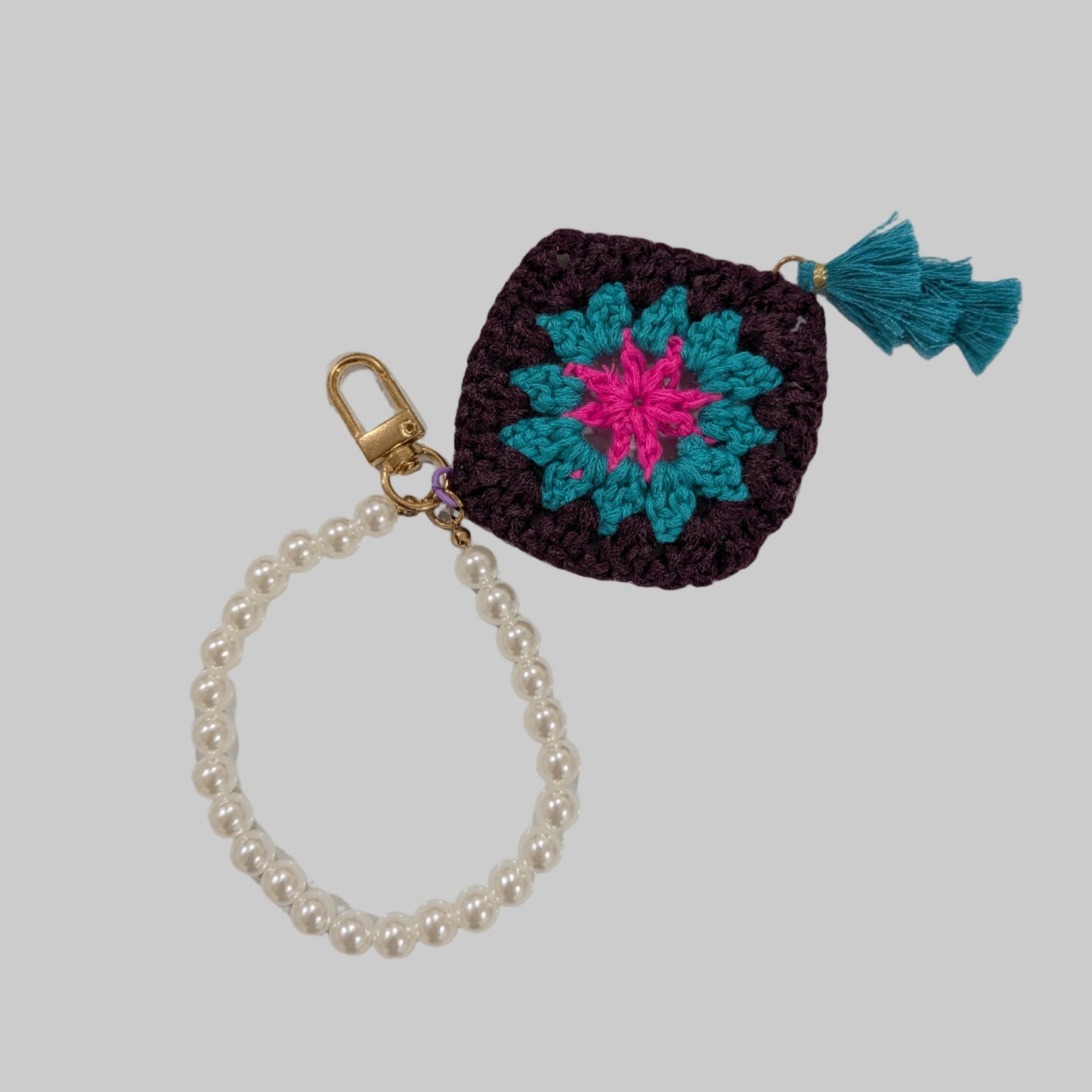 Black crocheted keychain and beads bracelet with a colorful flower design on a light blue background