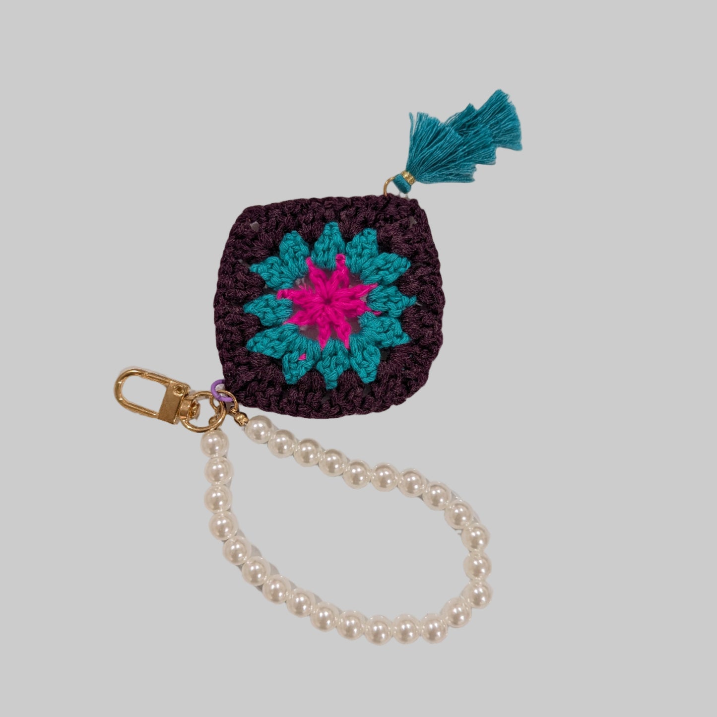 Black crocheted keychain and beads bracelet with a colorful flower design on a light blue background