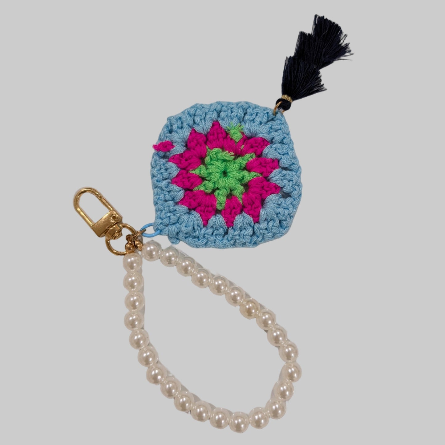 Blue Crocheted keychain and beads bracelet with a colorful flower design on a light blue background