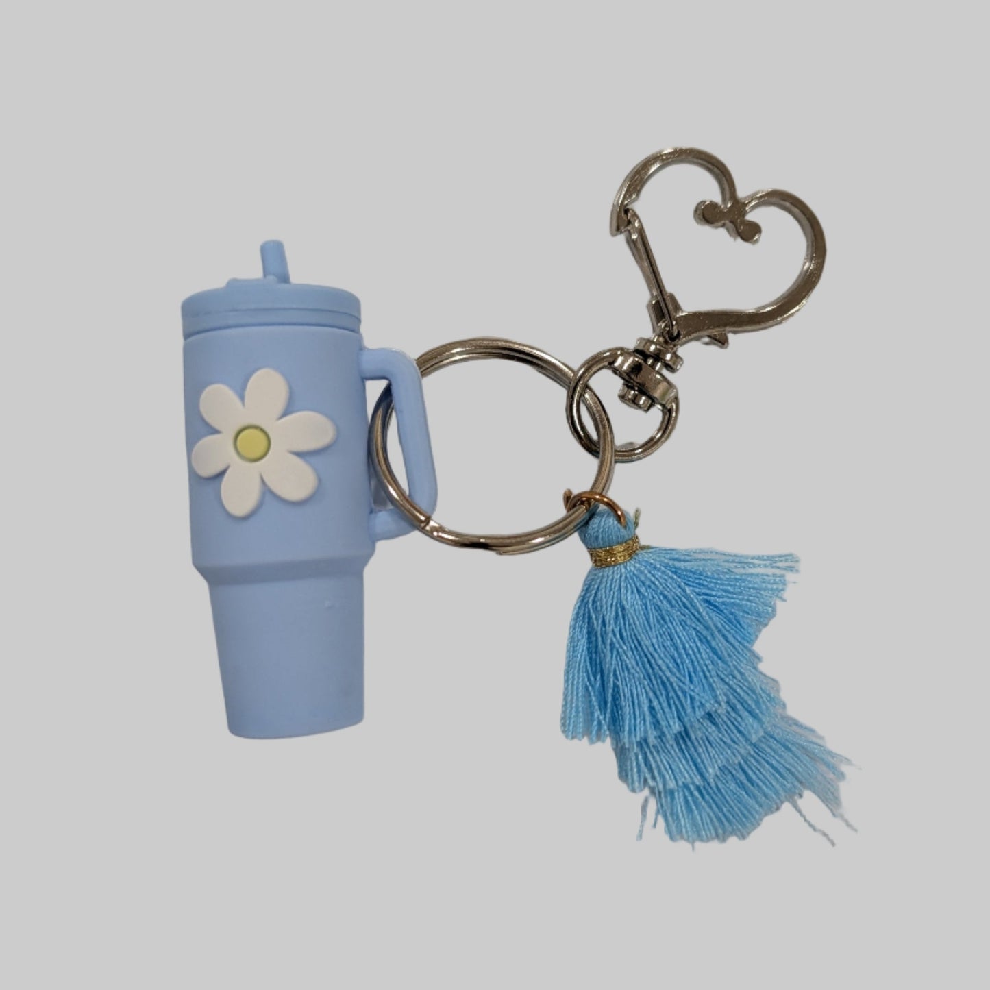 Blue little silicone tumbler keychain with a flower charm and tassel on a white background