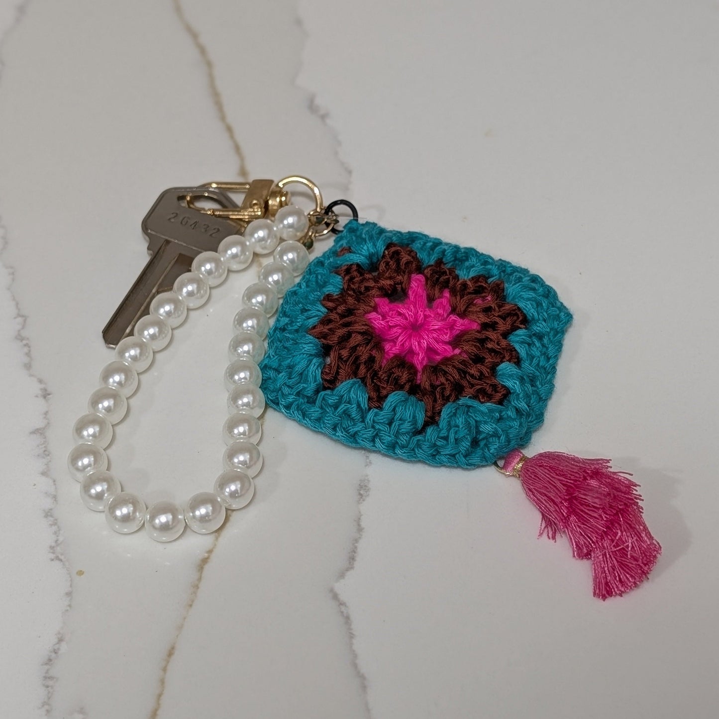 Crocheted keychain with colorful design on a white textured surface