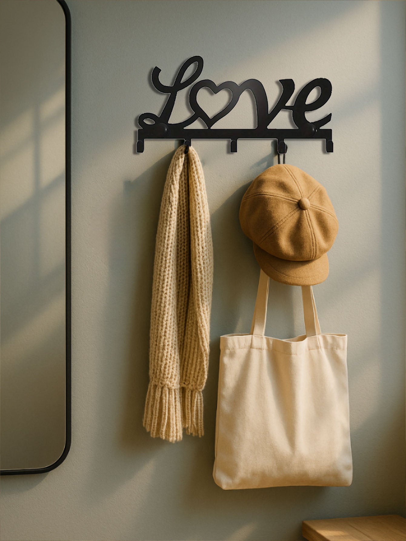 Decorative 5-hook wall mounted key rack with 'Love' text design, holding a scarf, cap, and tote bag against a neutral wall.