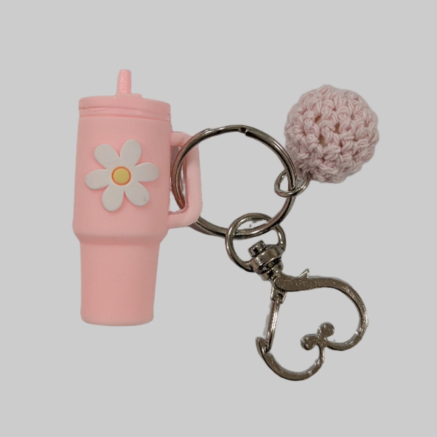 Light Pink little silicone tumbler keychain with a flower charm on a gray background