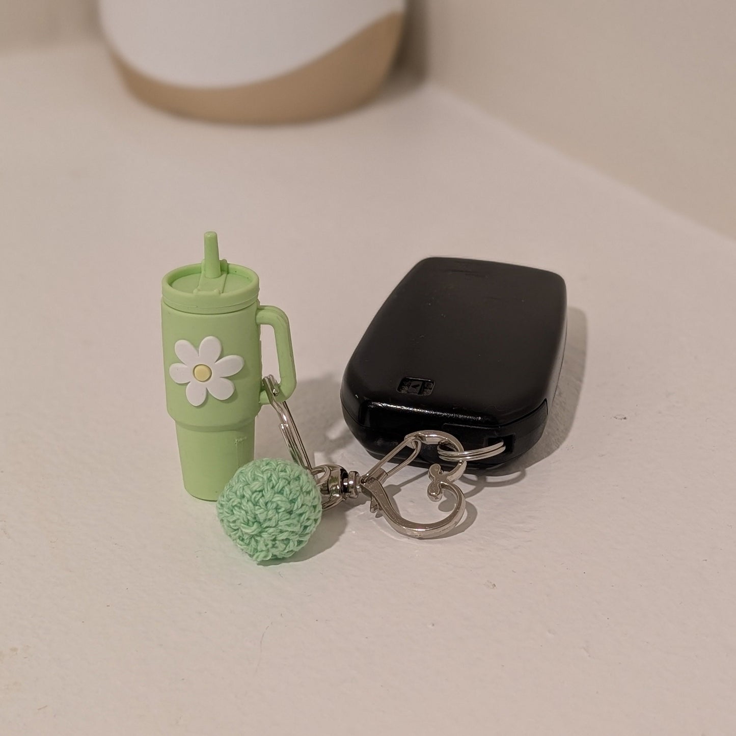Little green silicone tumbler Keychain with green cup and ball design on a light surface