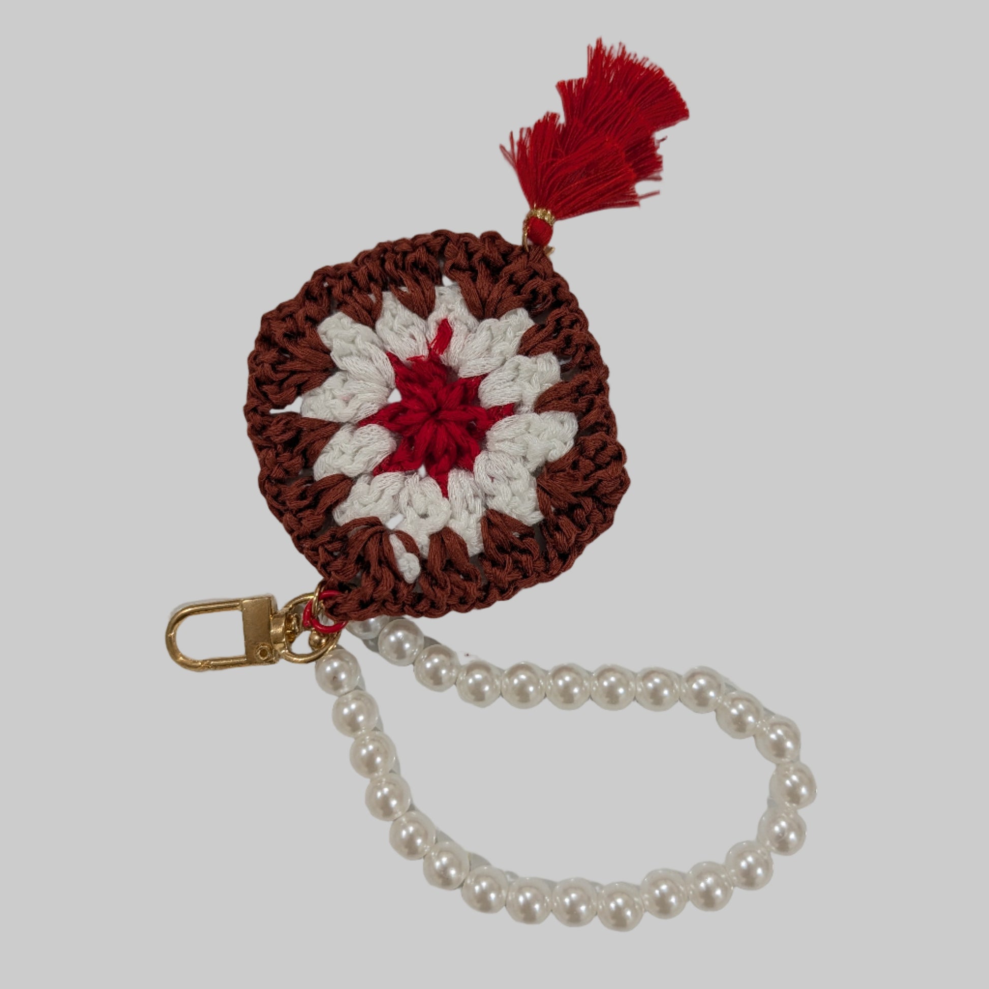 Maroon crocheted keychain and beads bracelet with a colorful flower design on a light blue background