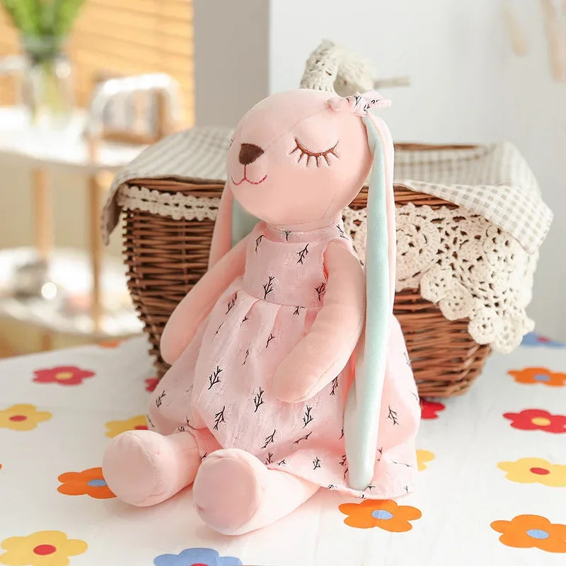 Pink bunny plush bunny toy with a dress on a floral blanket