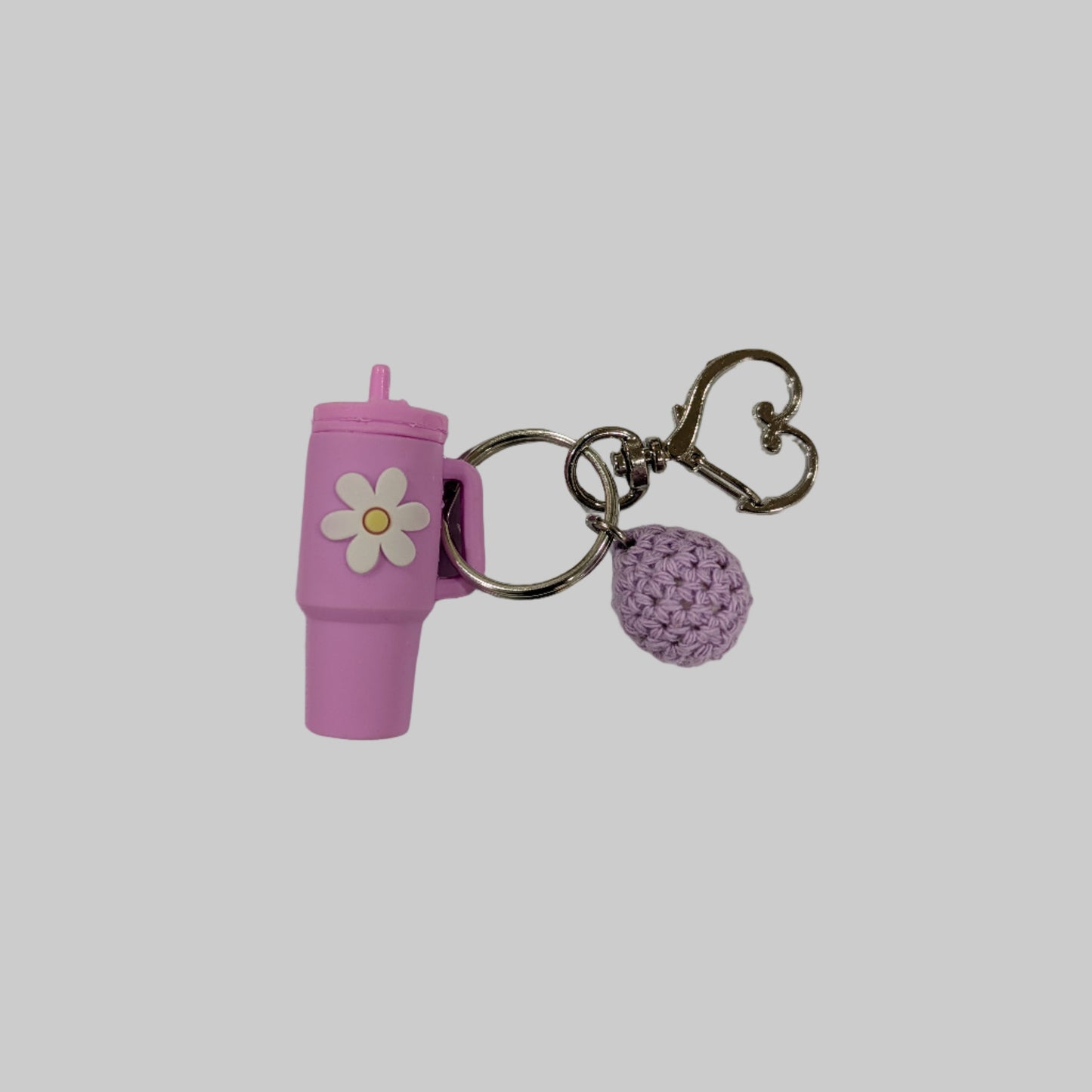 Pink little silicone tumbler shaped keychain with a small flower charm on a white background