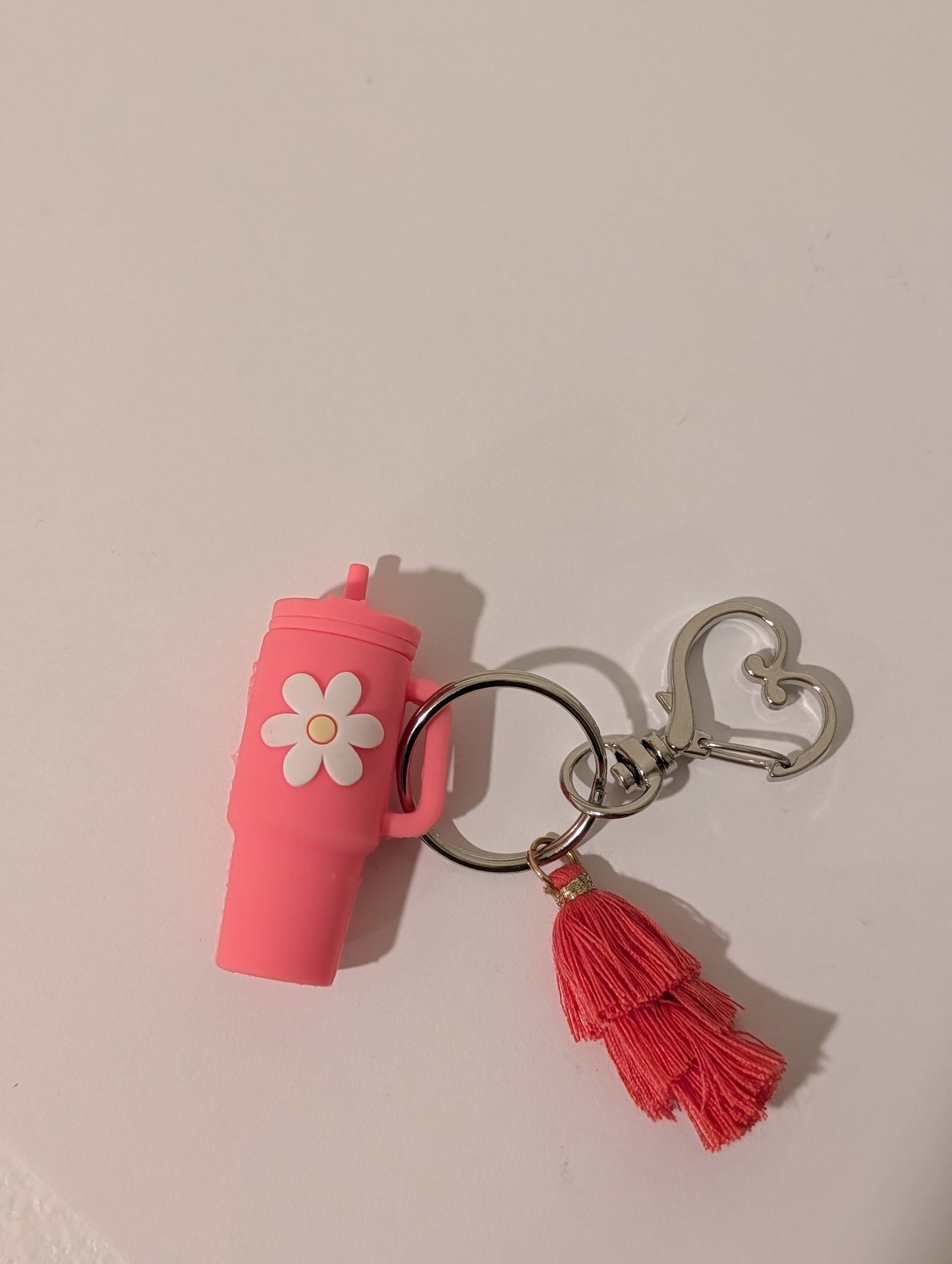 Pink silicone tumbler keychain with a tassel and a heart shaped buckle on a white background