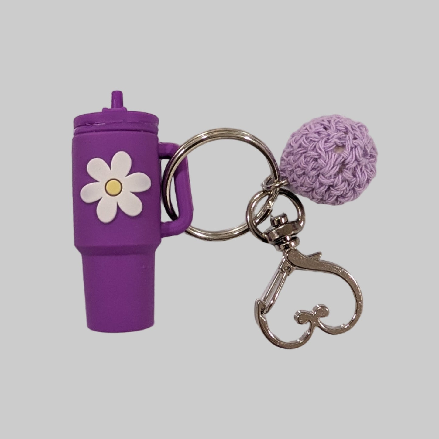 Purple little silicone tumbler keychain with a flower charm and a ball on a white background