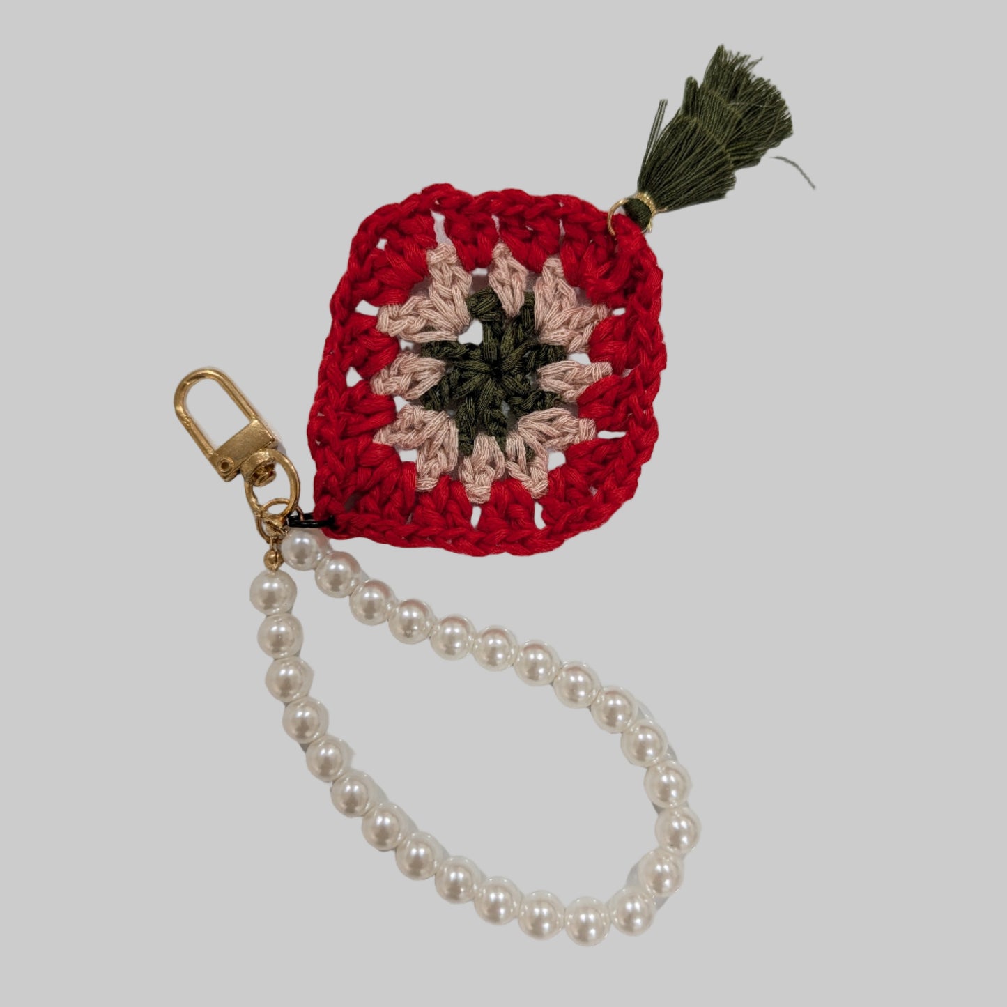 Red crocheted keychain and beads bracelet with a colorful flower design on a light blue background