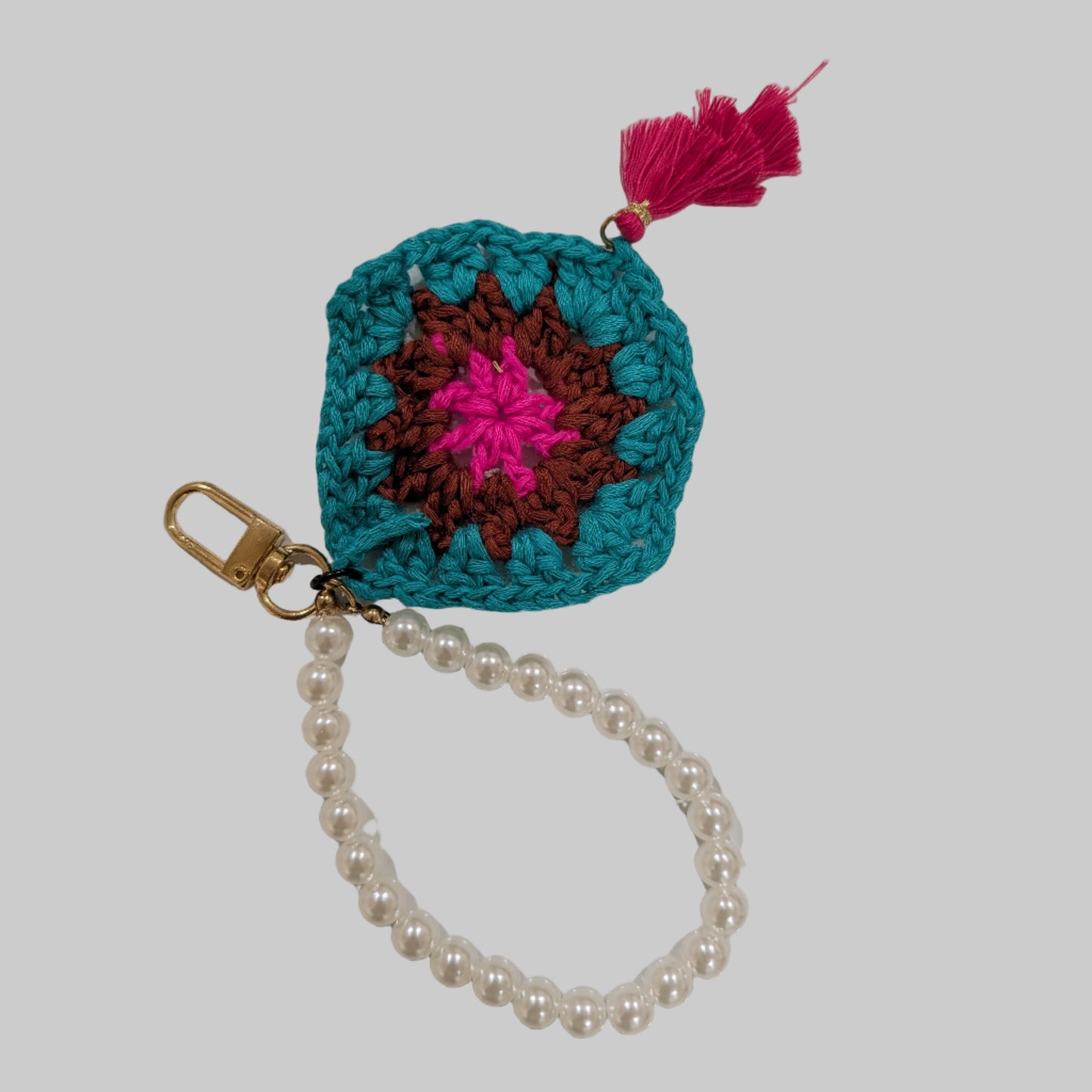 Teal crocheted keychain and beads bracelet with a colorful flower design on a light blue background