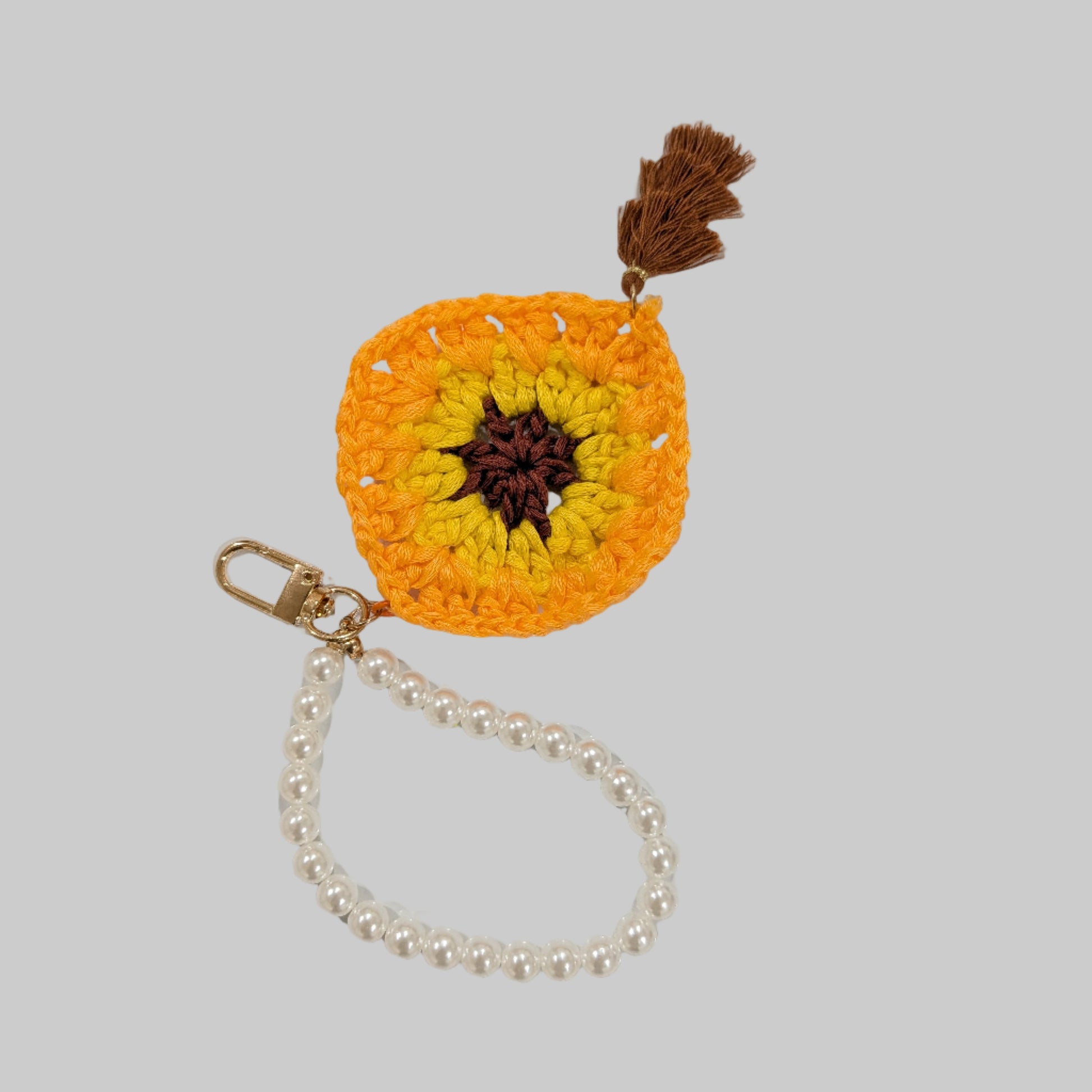 Yellow crocheted keychain and beads bracelet with a colorful flower design on a light blue background