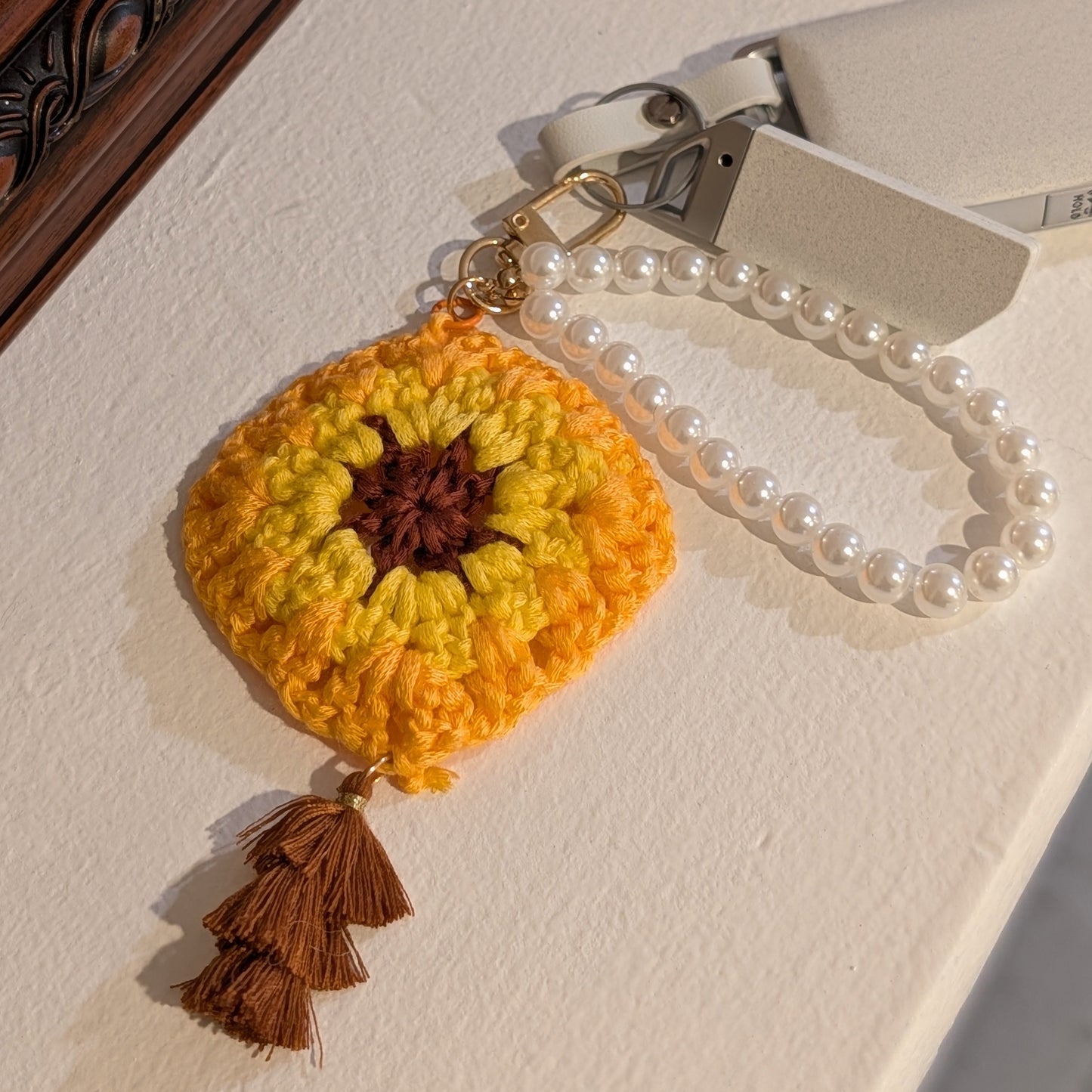 yellow Crocheted keychain with a brown tassel on a wooden surface