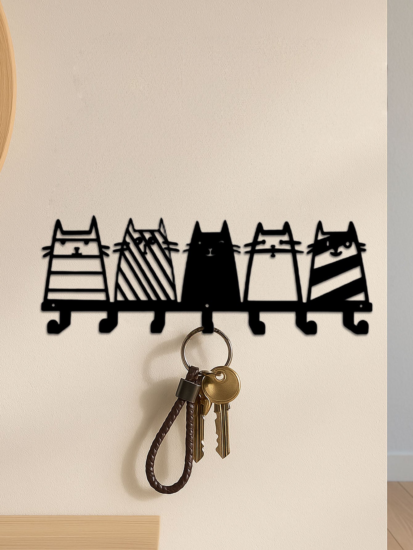 7-hook wall-mounted key holder shaped like cats with keys hanging from it on a light-colored wall.