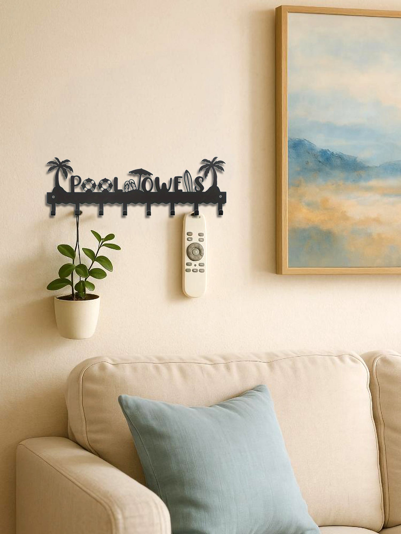 8 hooks beach themed wall hook with text 'Pool Towels' and decorative elements hanging on its hooks above a sofa in a living room setting