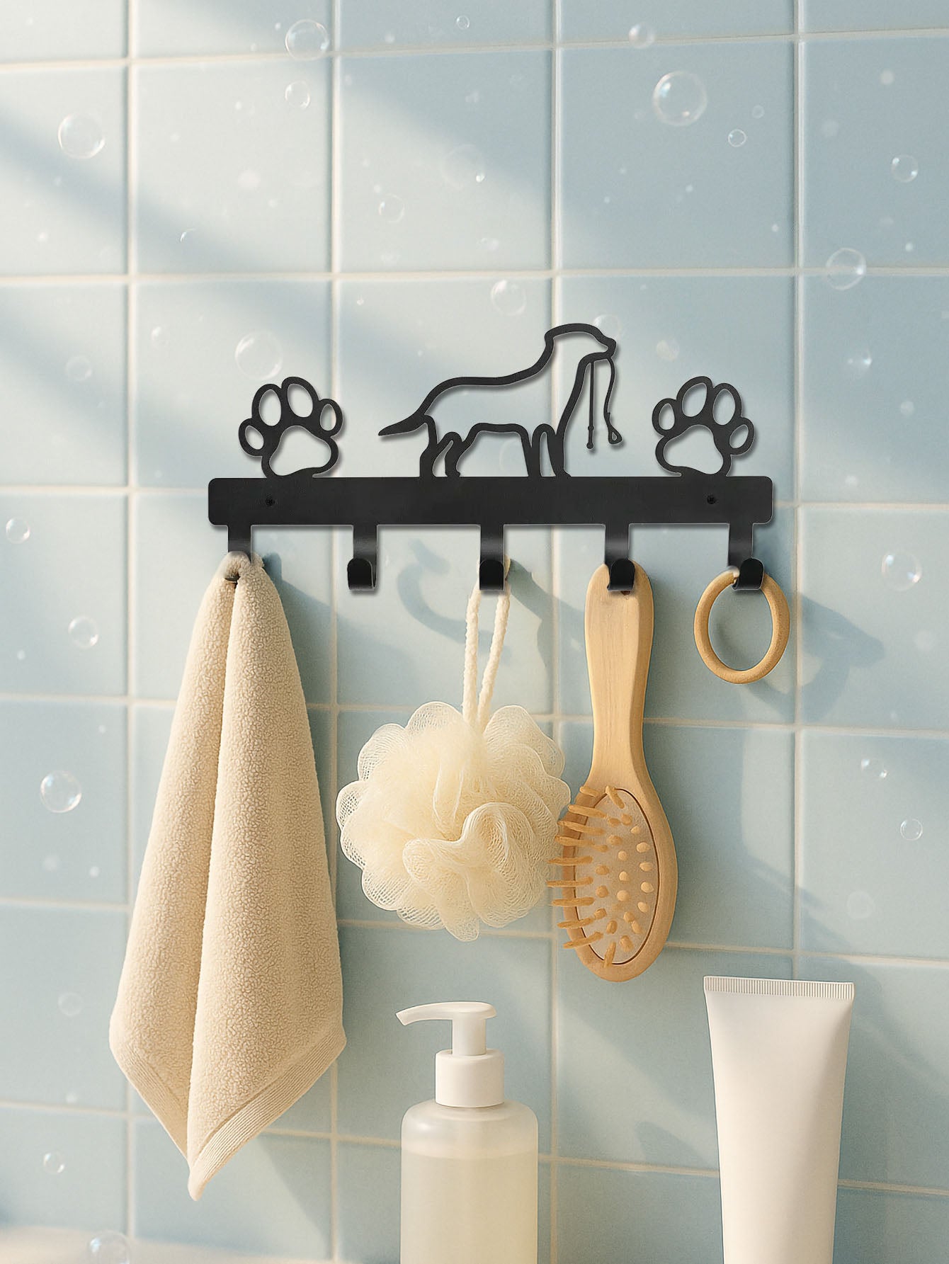 Black metal 5-hook wall mounted key and coat rack with dog & paws designs on a tiled bathroom wall.