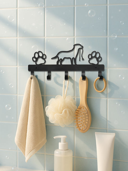 Black metal 5-hook wall mounted key and coat rack with dog & paws designs on a tiled bathroom wall.