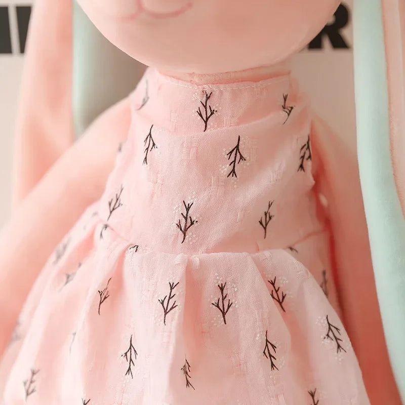 Close-up of the pink bunny plush dress with black floral patterns on a blurred background