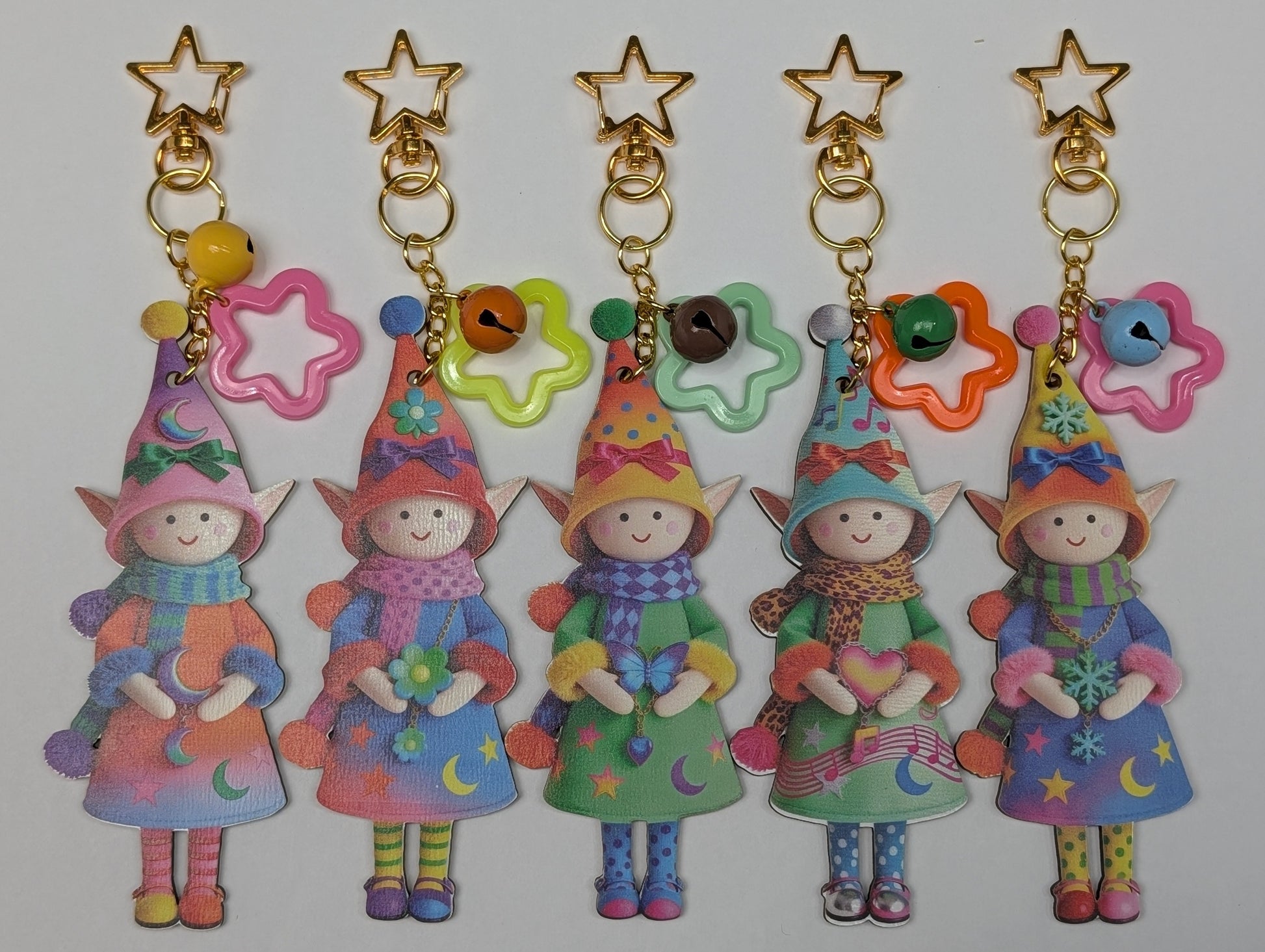 Colorful holiday theme doll keychains with star-shaped accessories and chain on a white background