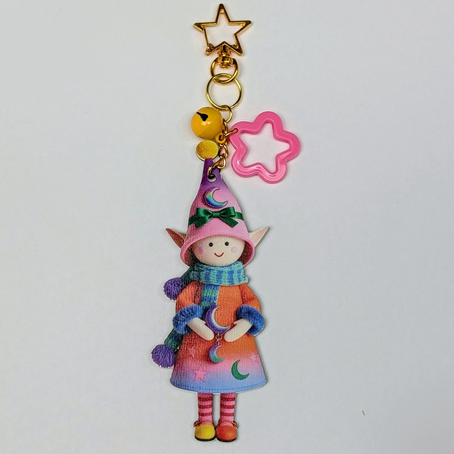 Colorful holiday themed fairy doll keychain with golden star, pink flower, and yellow bell charm on a white background