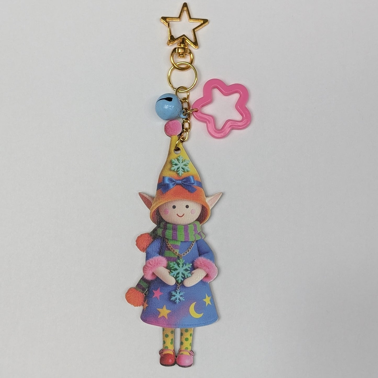 Colorful holiday themed fairy doll keychain with star, flower, and bell charm on a white background