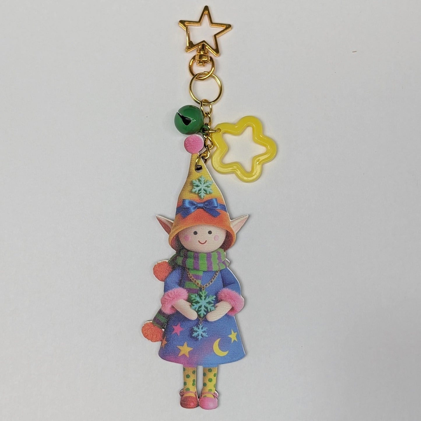 Colorful holiday themed fairy doll keychain with yellow star, flower, and green bell charm on a white background
