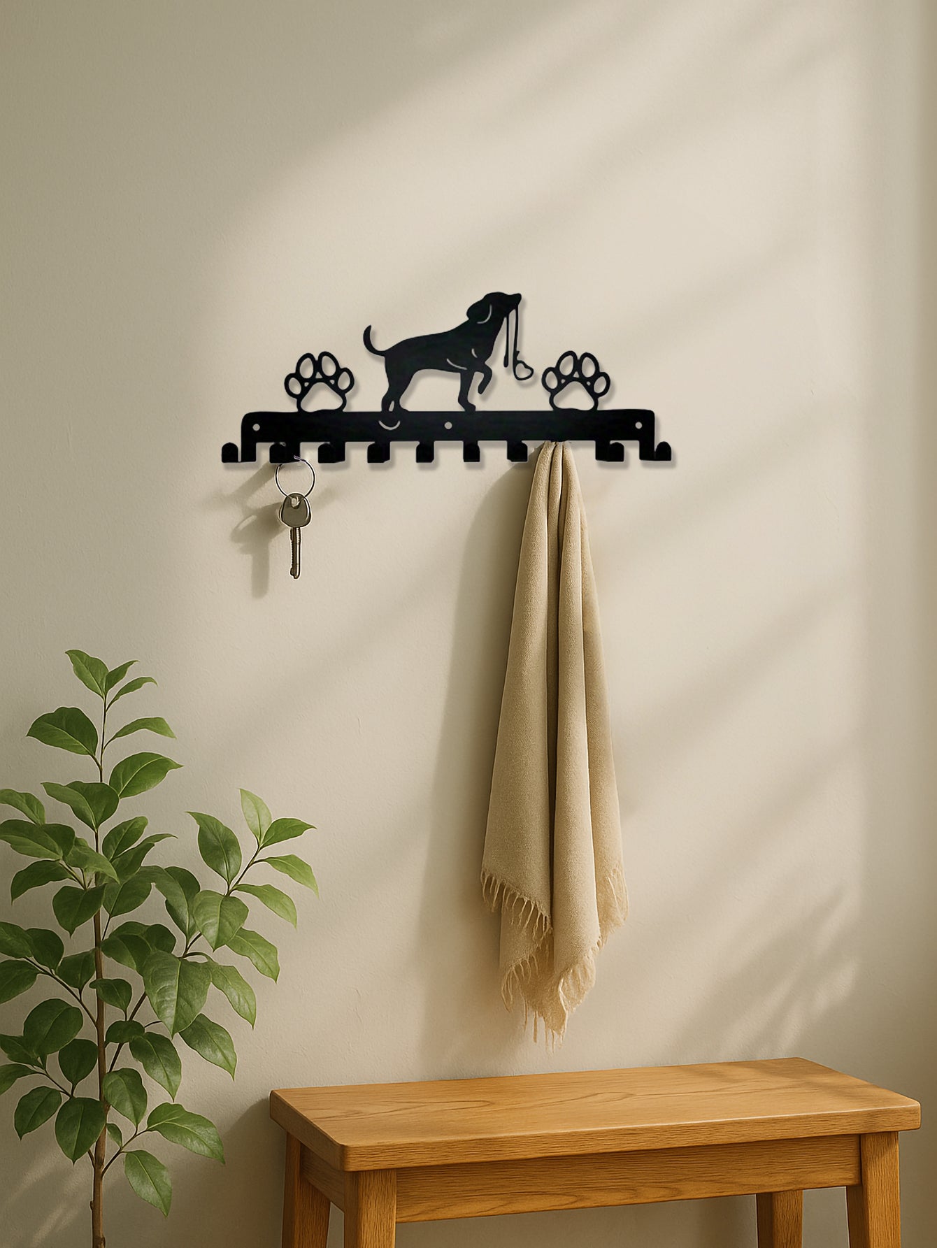 Decorative 10-hook wall rack with dog and paws design on a beige wall, next to a wooden bench and plant.