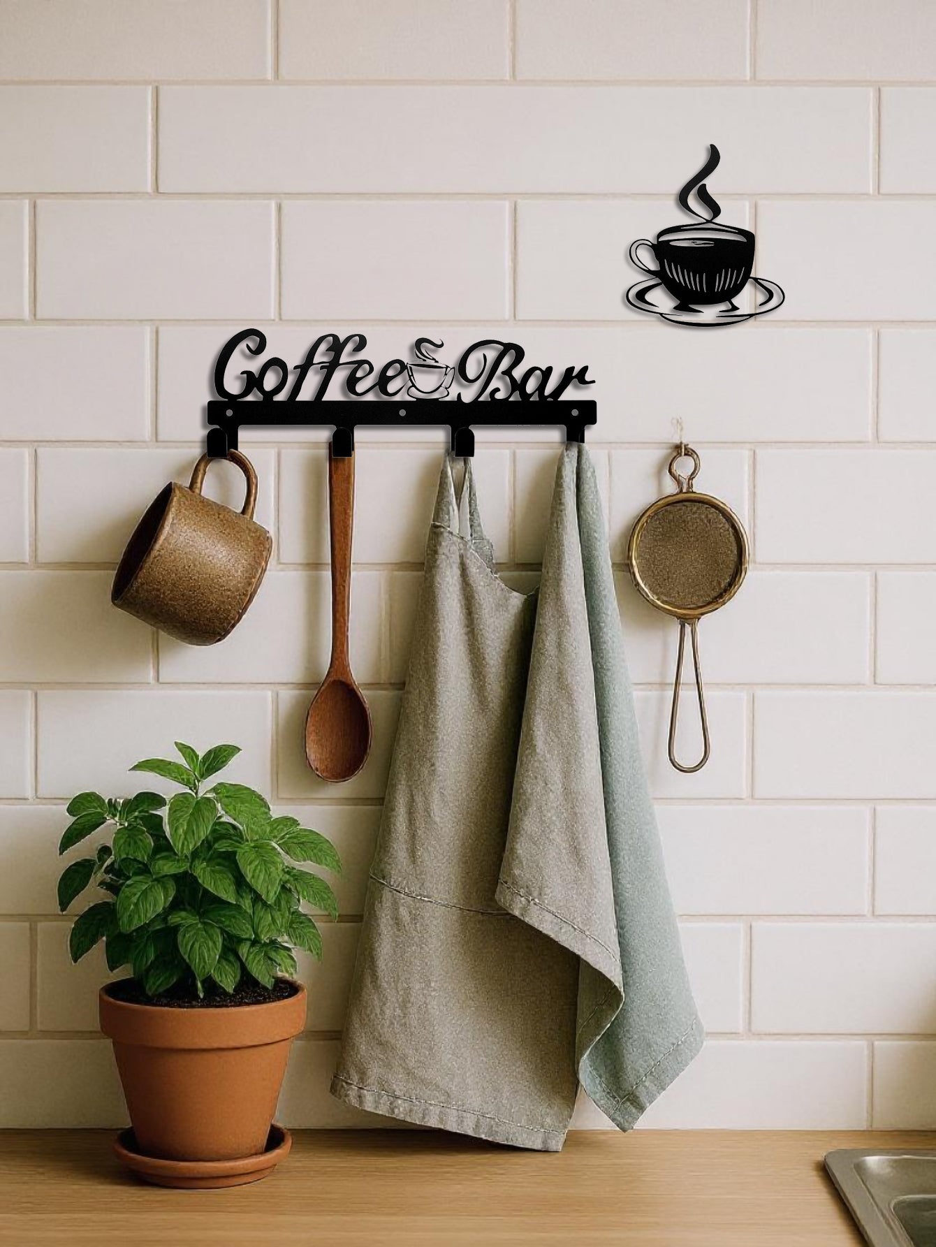 Decorative 4-hook wall mounted key and coat rack with 'Coffee Bar' text & separate coffee cup decor piece, mugs, apron, and pan on a kitchen wall.