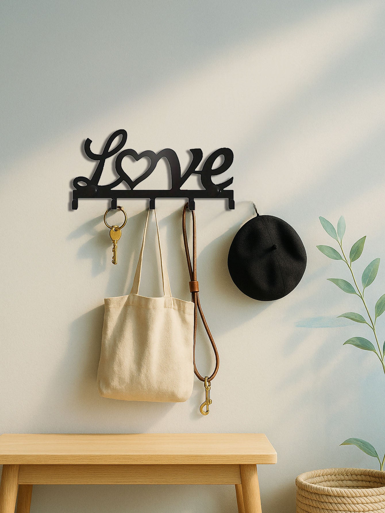 Decorative 5-hook wall mounted key rack with 'love' text design holding a bag, key, and hat against a light wall.