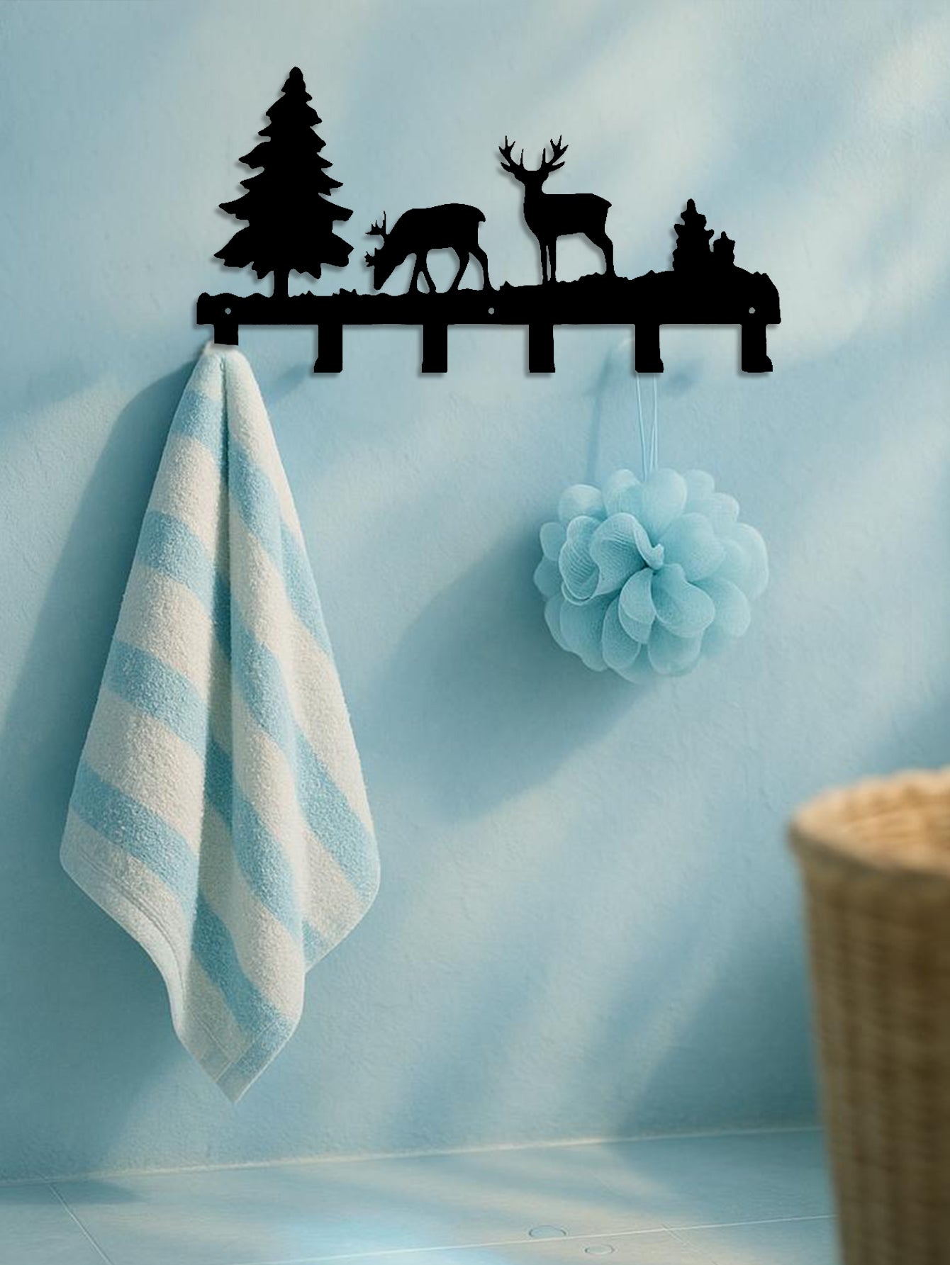 Decorative 6-hook wall-mounted key and coat rack with deer and tree design on a light blue wall with a towel and pom-pom hanging.