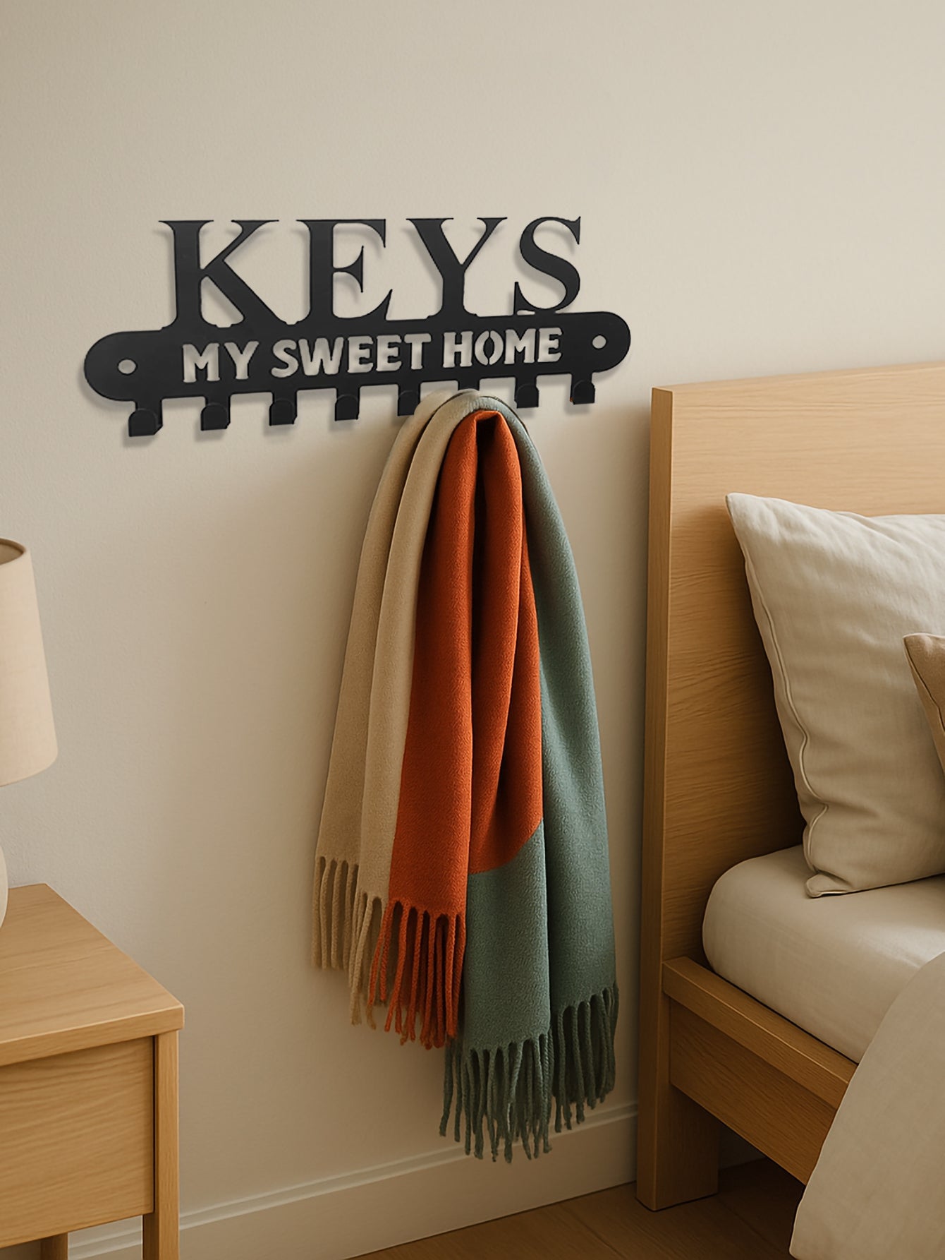 Decorative 8-hook wall mounted key rack with 'KEYS MY SWEET HOME' above a bed with colorful scarves.