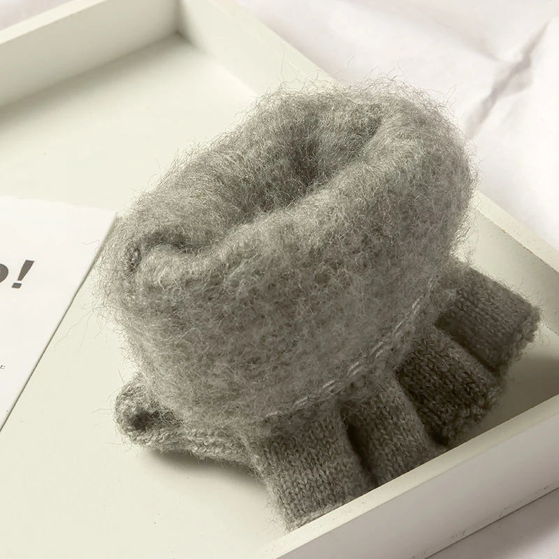 Gray knitted fingerless glove showing its inner fur side on a white surface