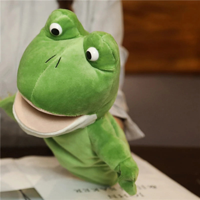 Green plush frog hand puppet on a person's hand.