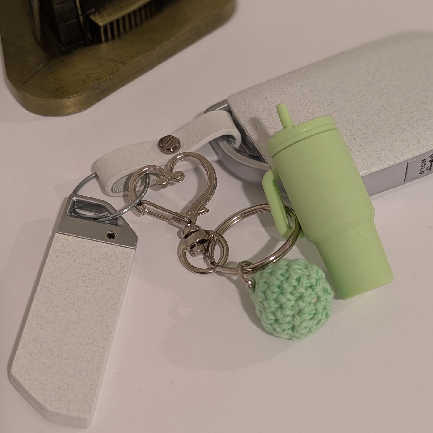 Keychain with a green silicone tumbler charm and crochet ball on a light surface
