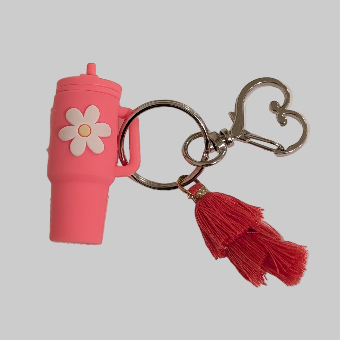 Pink silicone tumbler keychain with a tassel and a heart shaped buckle on a white background