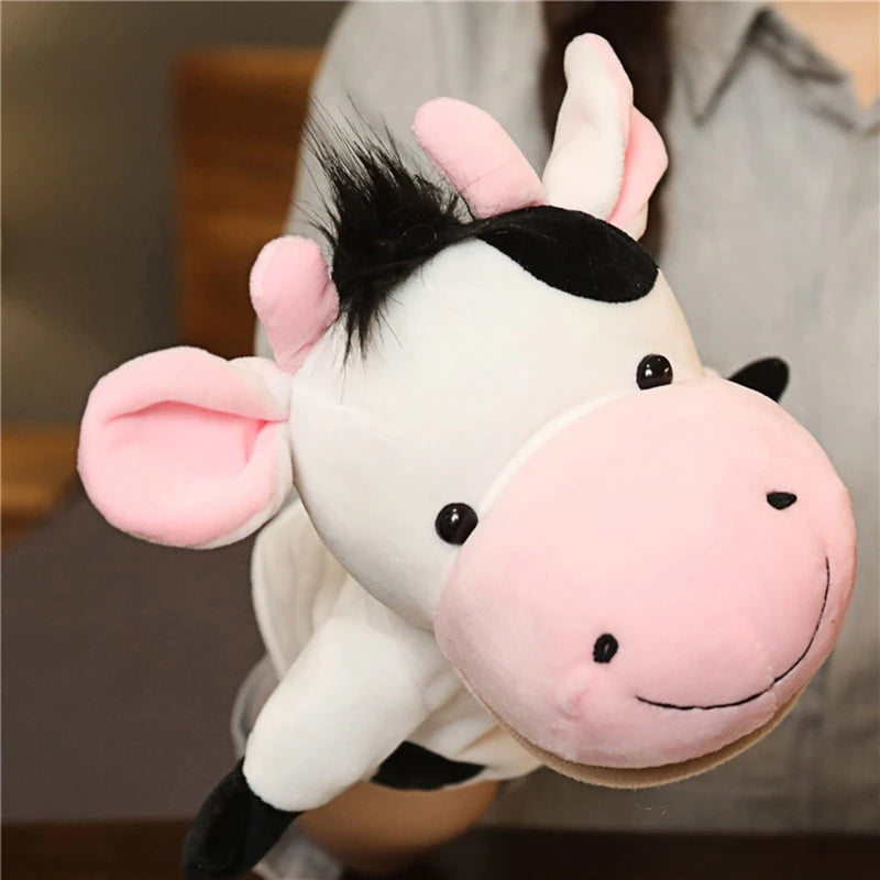 Plush hand puppet cow with pink ears and face held by a person