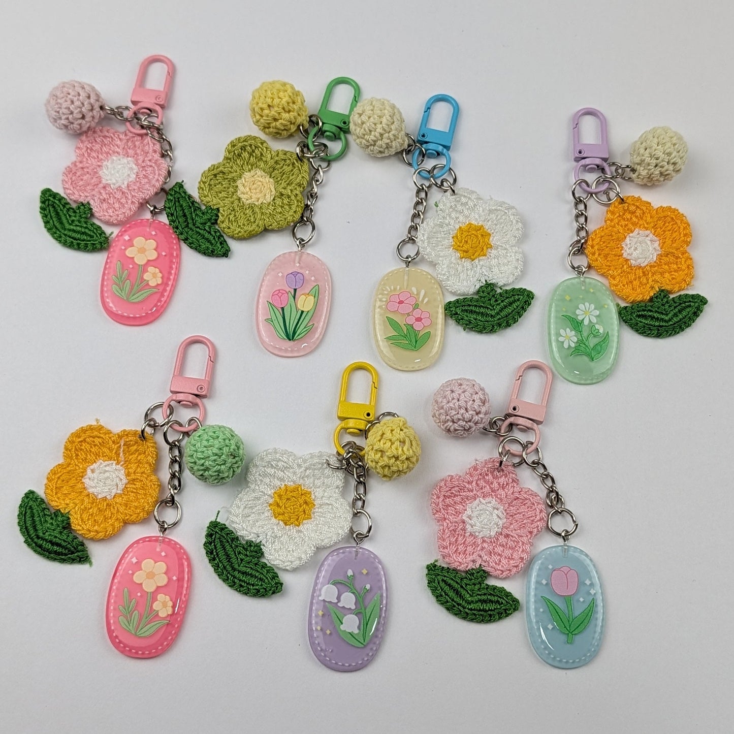 Set of colorful keychains with crochet floral designs and crochet ball on a light gray background