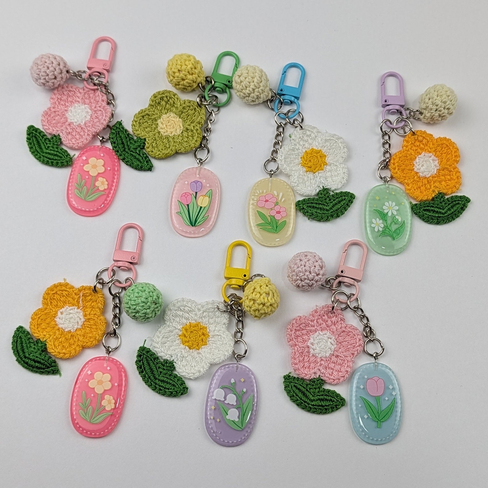 Set of colorful keychains with crochet floral designs and crochet ball on a light gray background
