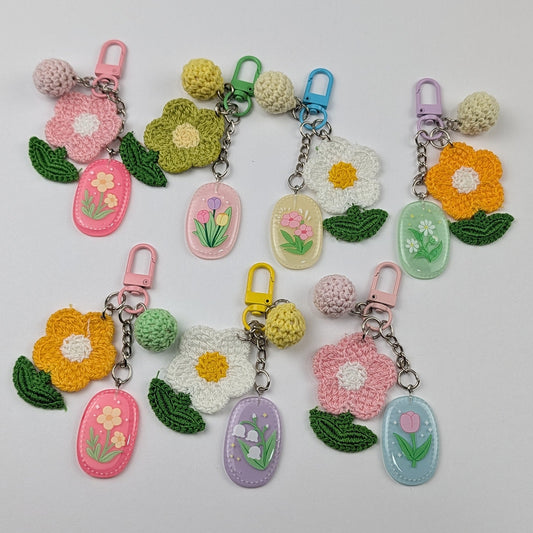 Set of colorful keychains with crochet floral designs and crochet ball on a light gray background