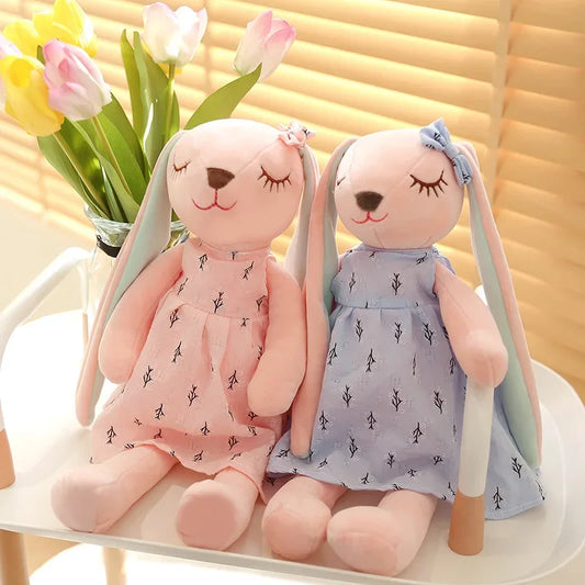 Two plush bunny toys in dresses on a chair with tulips in the background