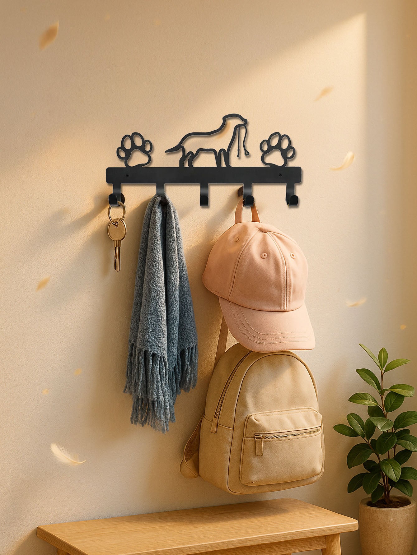 Wall-mounted paws & dog design 5-hook keys and coat rack with hooks holding a cap, backpack, and towel against a beige wall.