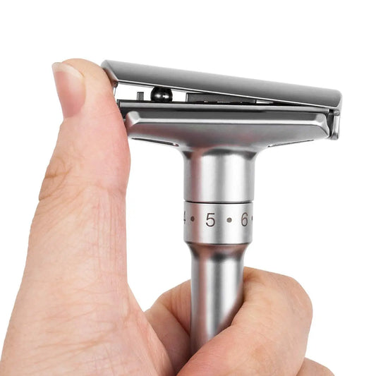 Picture with adjustable blade safety razor for men, being held in someone's hand. Picture shows the razor head slightly open from one side with a thumb.
