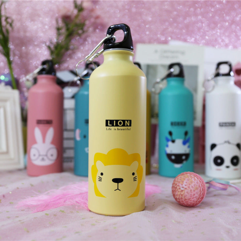 Image for stainless steel reusable water bottle for kids in light yellow color with lion face print on it. It has "LION" text right above the face and a "Life is beautiful" quote right below it. The bottle is shown standing straight with a small decoration ball lying next to it and few other similar bottles in the background.