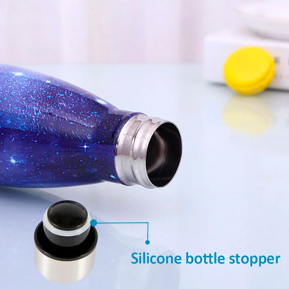 Image for stainless steel vacuum flask with sky galaxy style printing in blue color. The bottle has a stainless steel cap with a silicone sealing ring inside to keep it air tight when capped. The image shows bottle with the cap removed and placed on the side and the bottle is lying on floor to show its open mouth.