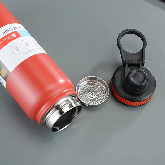 Image for red stainless steel double wall insulated water bottle lying on the floor with removed lid and tea filter place don the side. The lid has a carrying loop attached to it.