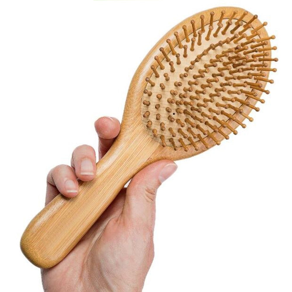 Image of oval head bamboo wooden hair brush in hand