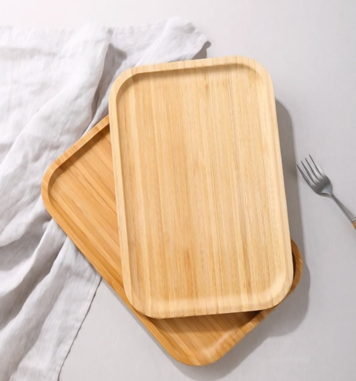 Image with two bamboo serving trays on top of each other with a steel fork next to them.