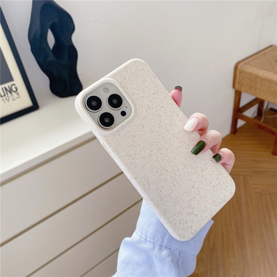 Image for compostable wheat straw material phone case for iPhone, in person's hand showing its back camera view. Color of case is white textured.