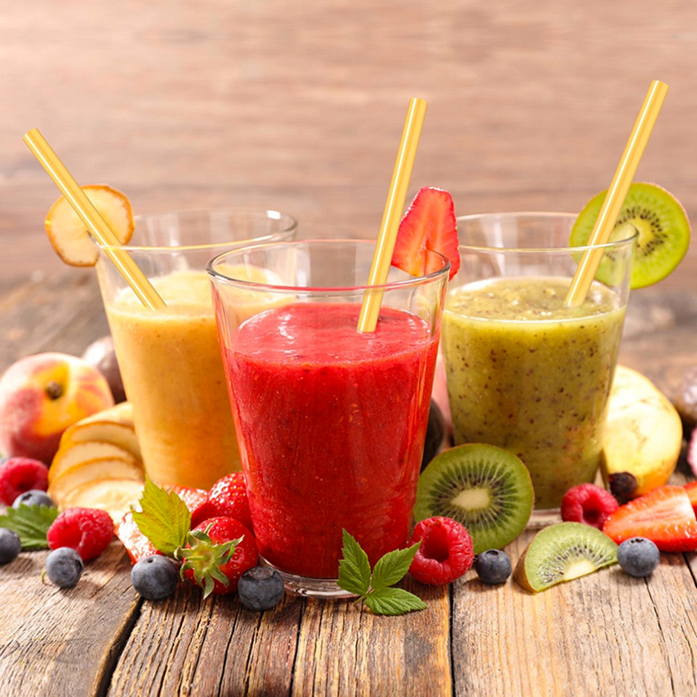 Image for three different smoothies in cups along with different fruits placed around them on a wooden surface. A reusable bamboo drinking straw is place in each smoothie cup.
